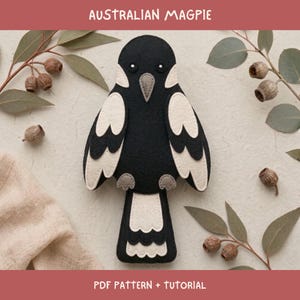 May include: A felt Australian magpie bird craft project featuring black and white layered wings, a grey beak, and white eyes. The text AUSTRALIAN MAGPIE and PDF PATTERN + TUTORIAL are printed on the image. The bird has a long tail with white scalloped edges.