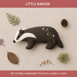 May include: A felt badger ornament featuring a dark brown body with a white face stripe and embroidered purple flowers on its back. The text LITTLE BADGER and PDF PATTERN, EMBROIDERY TEMPLATE & GUIDE | 2 SIZES is visible on the image.