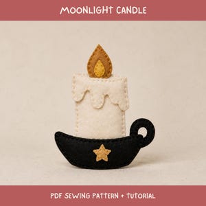 May include: A felt craft project titled MOONLIGHT CANDLE PDF SEWING PATTERN + TUTORIAL. The object is a cream-coloured candle with a brown and yellow flame, sitting in a black holder with a small yellow star and a circular handle on the side.