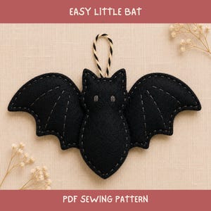 May include: A black felt bat ornament with grey stitched details on the wings and body, featuring a black and white twisted cord loop at the top for hanging. The text EASY LITTLE BAT and PDF SEWING PATTERN is printed on the background.
