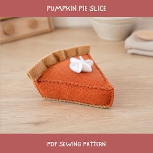 Könnte beinhalten: Ein Stück Kürbiskuchen aus Filz mit einer leuchtend orangefarbenen Füllung und einem beigen Krustenrand. Die Oberseite ist mit einem kleinen weißen Klecks Schlagsahne aus Filz verziert. Der Text PUMPKIN PIE SLICE und PDF SEWING PATTERN ist sichtbar.