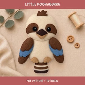 Puede incluir: Un proyecto de manualidades en fieltro con un pájaro kookaburra de alas color crema, marrón y azul, pico marrón oscuro y ojos negros. El texto LITTLE KOOKABURRA y PDF PATTERN + TUTORIAL es visible. Incluye un carrete de madera y dos botones.