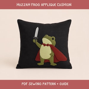May include: A black square cushion featuring a central appliqué of a green frog wearing a red cape and a small red bow tie, holding a grey sword. The text HUZZAH FROG APPLIQUE CUSHION and PDF SEWING PATTERN + GUIDE is printed above and below the cushion.