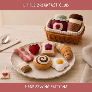 May include: A set of felt play food items including bacon, a strawberry, toast with jam, a croissant, a fried egg, a cinnamon roll, and a tea bag. A woven basket contains a felt jam jar and coffee cup. Text reads LITTLE BREAKFAST CLUB 9 PDF SEWING PATTERNS.