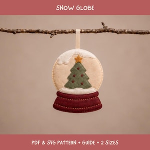 May include: A felt snow globe ornament featuring a cream-colored dome with a green Christmas tree, a yellow star topper, and a dark red base. The ornament hangs from a branch and includes the text SNOW GLOBE and PDF & SVG PATTERN + GUIDE + 2 SIZES.