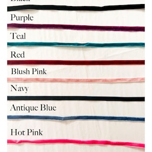 K&ouml;nnte beinhalten: Eine Auswahl an Samtb&auml;ndern in verschiedenen Farben, darunter Schwarz, Lila, T&uuml;rkis, Rot, Ros&eacute;, Marineblau, Antikblau und Pink. Jedes Band ist mit seinem Farbnamen in einer sauberen, wei&szlig;en Schrift beschriftet.