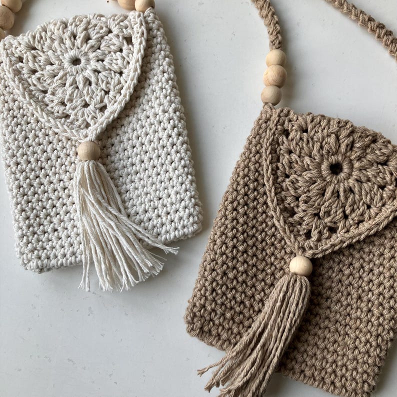 Puede incluir: Dos bolsos de crochet cruzados en crema y marr&oacute;n. Cada bolso presenta un dise&ntilde;o floral en la solapa, un adorno de cuentas de madera y una borla larga. Las correas son de un cord&oacute;n de crochet trenzado con cuentas de madera.