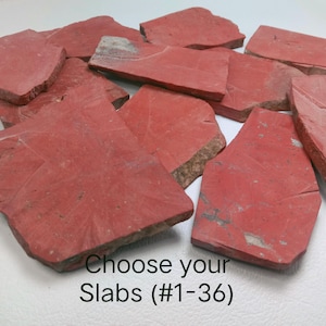 Könnte beinhalten: Eine Sammlung unregelmäßiger, flacher roter Steinplatten mit unterschiedlichen Texturen und natürlichen Kanten. Die Steine zeigen Schattierungen von tiefem Rot und Terrakotta. Der Text "Choose your Slabs (#1-36)" ist unten in Schwarz aufgedruckt.