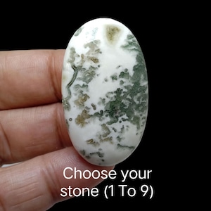 May include: An oval-shaped gemstone with a white base and green and brown inclusions. The stone is held in a hand against a black background. Text at the bottom reads "Choose your stone (1 To 9)".