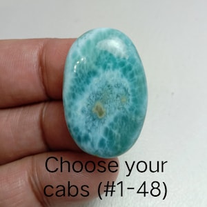 May include: Oval-shaped, polished gemstone with a turquoise and white marbled pattern. The stone has a smooth, glossy surface. Text on the image reads "Choose your cabs (#1-48)".