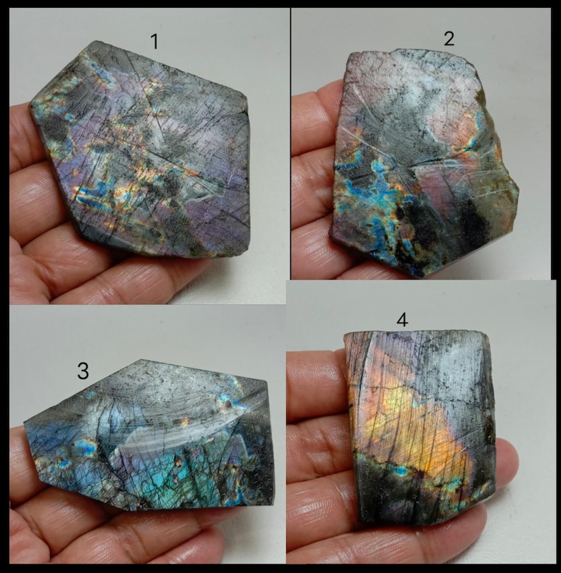 May include: Four pieces of labradorite gemstone, each with a unique shape and iridescent play of color. The stones display a range of colors including blues, purples, and golds, with a textured surface. The gemstones are held in a hand.
