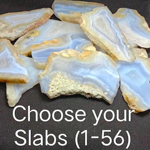 May include: A selection of blue lace agate slabs, displaying pale blue and tan tones. The slabs have a natural, uneven texture and are of varying shapes. The image includes the text "Choose your Slabs (1-56)".