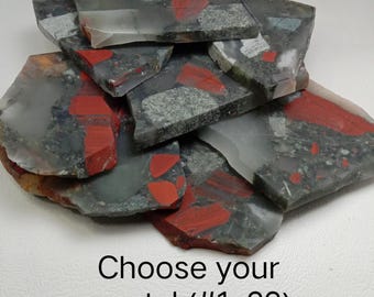 Peut inclure: Une collection de dalles de pierre plates et irrégulières présentant un mélange d'inclusions grises, blanches translucides et rouge vif. Les pierres ont une texture de surface polie et lisse. Le texte "Choose your crystal (#1-32)" est imprimé.