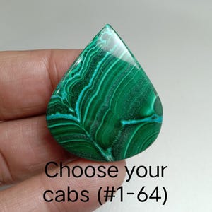 May include: A teardrop-shaped malachite cabochon with a polished surface. The stone features a vibrant green color with swirling patterns of lighter green and teal. The text "Choose your cabs (#1-64)" is visible.