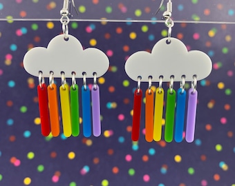 May include: White cloud shaped earrings with rainbow colored dangling charms. The charms are long and thin, resembling raindrops.