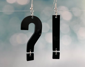 May include: A pair of black acrylic earrings. One earring is shaped like a question mark and the other is a rectangle. Both earrings have a small black square hanging from the bottom.