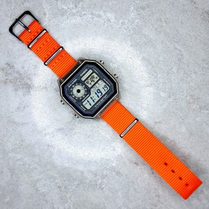 Casio World Time Illuminator Silver Watch with Neon Orange Band, AE-1200WHD-1AVEF