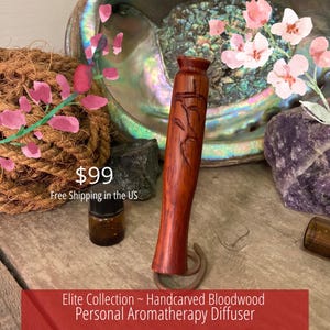 Könnte beinhalten: Handgeschnitzter persönlicher Aromatherapie-Diffusor aus Blutholz. Das rotbraune Holz ist mit einem floralen Design geschnitzt. Der Diffusor wird mit einer kleinen braunen Flasche und einem dekorativen Hintergrund präsentiert.