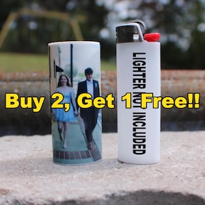 May include: A white lighter with the text "LIGHTER NOT INCLUDED" and a red button next to a cylindrical lighter case with a photo of a couple. The text "Buy 2, Get 1 Free!!" is in yellow.