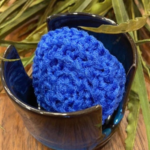 May include: A blue crocheted yarn bowl with a blue yarn ball inside. The bowl is made of ceramic and has a glossy finish.