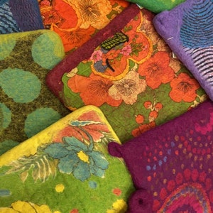 May include: A collection of colorful felt coasters with floral and abstract designs. The coasters are made of wool felt and are hand-painted with vibrant colors.