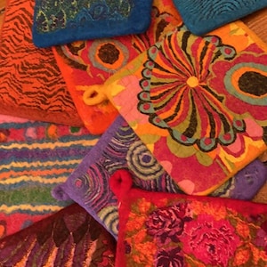 May include: A collection of colorful, patterned pot holders. The pot holders are made of felted wool and feature a variety of designs, including stripes, flowers, and abstract patterns.
