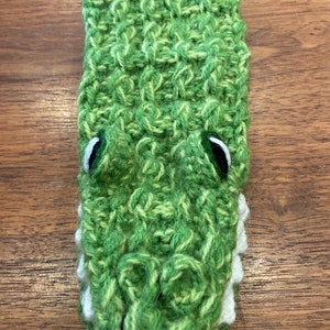 Pu&ograve; includere: Marionetta di coccodrilo in crochet verde con denti bianchi e occhi neri.
