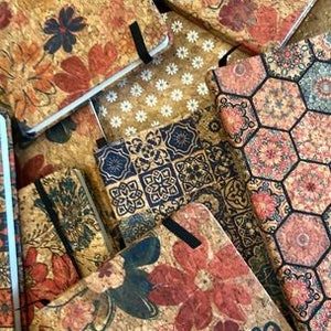 May include: A collection of cork-covered journals with various floral and geometric designs. The journals have a rustic, vintage aesthetic and are perfect for writing, journaling, or sketching.
