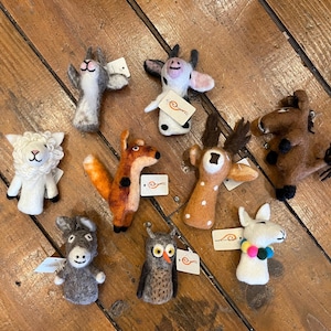 May include: A set of nine felt finger puppets featuring various animals, including a fox, deer, cow, donkey, owl, llama, sheep, and two other animals. The puppets are all handmade and have a whimsical, colorful design.
