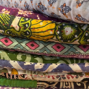 May include: A stack of colorful fabric squares with different patterns, including floral, geometric, and paisley designs. The fabric is layered and stitched together, creating a unique and textured look.