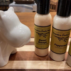 May include: Three 2 fl oz bottles of Garden Path Soap scented lotion. The bottles are labeled with the scents: Sweet Orange, Peppermint, and Milk & Almond.