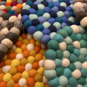 May include: Set of six colorful felt coasters, each made of small, round balls. The coasters are in shades of gray, yellow, orange, blue, green, and white.