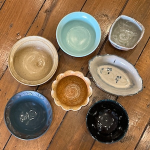 May include: A set of three ceramic vases in varying heights and shapes. The vases are glazed in a matte white finish, offering a minimalist aesthetic. The tallest vase is approximately 10 inches high.