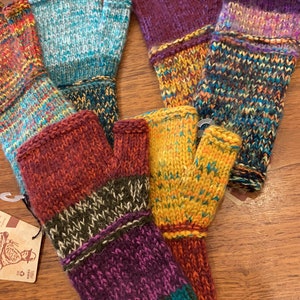 Op de afbeelding: Vijf paar vingerloze handschoenen in verschillende kleuren en patronen. De handschoenen zijn gemaakt van een zachte, gebreide stof en hebben een verscheidenheid aan kleuren, waaronder paars, teal, oranje, bruin en groen.