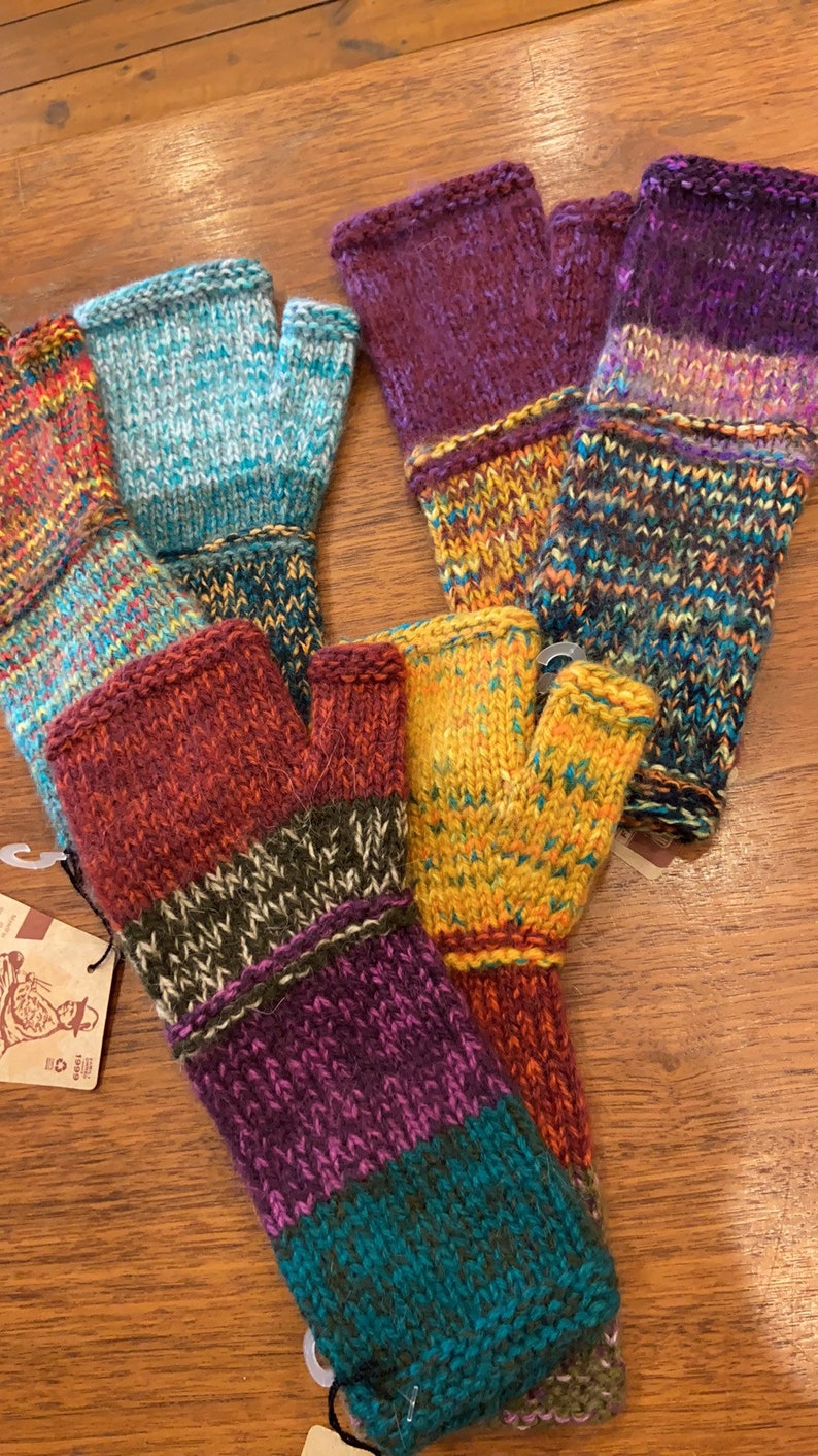 Op de afbeelding: Vijf paar vingerloze handschoenen in verschillende kleuren en patronen. De handschoenen zijn gemaakt van een zachte, gebreide stof en hebben een verscheidenheid aan kleuren, waaronder paars, teal, oranje, bruin en groen.