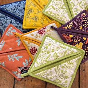 May include: A collection of colorful, triangular pot holders with floral patterns. The pot holders feature various designs in shades of orange, yellow, blue, green, and purple. Each pot holder has a loop for hanging.