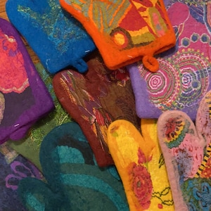 May include: A collection of colorful, patterned oven mitts made of felt. The mitts feature a variety of designs, including paisley, floral, and geometric patterns.