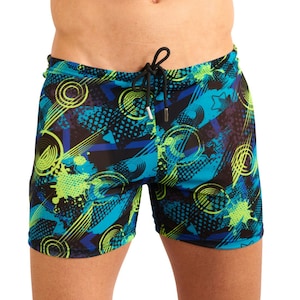 May include: Blue and black swimming trunks with a geometric print featuring circles, stars, and diagonal lines. The print is in shades of blue, green, and yellow.