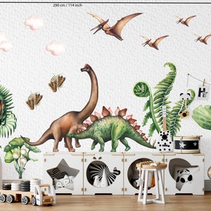 May include: A whimsical wall mural featuring watercolor dinosaurs, pterodactyls, and clouds. The design includes a Stegosaurus, Brachiosaurus, and a T-Rex, along with ferns and a wooden toy truck. The mural measures 114 inches wide and 70.86 inches high.