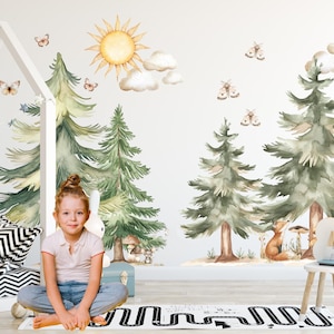 Könnte beinhalten: Ein Kinderzimmer mit einer skurrilen Wanddekoration im Waldthema. Das Design zeigt Kiefern im Aquarellstil, eine Sonne, Wolken, Schmetterlinge und einen Fuchs. Ein Mädchen sitzt vor der Wand auf dem Boden. Ein kleiner weißer Stuhl und eine Spielmatte sind ebenfalls zu sehen.