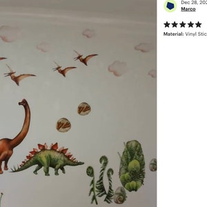 May include: A wall decal featuring a prehistoric scene with dinosaurs and flying reptiles. The design includes a brown Brontosaurus, a green Stegosaurus, and several Pterodactyls. Soft pink clouds and green foliage complete the scene. The decal is made of vinyl.