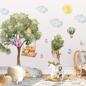 Può includere: Un set di adesivi murali con illustrazioni ad acquerello dei personaggi di Winnie the Pooh, tra cui Ih-Oh, Pimpi, Tigro e Uffa. Il design include un grande albero con un alveare, un'altalena, una mongolfiera, nuvole, un sole e delle farfalle.