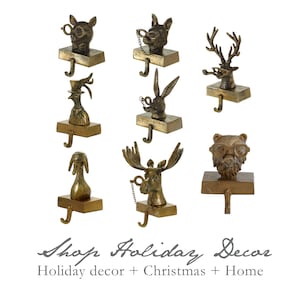 May include: Set of eight gold-toned metal stocking holders featuring various animal heads, including a moose, deer, rabbit, bear, and rooster. Each holder has a hook for hanging stockings.