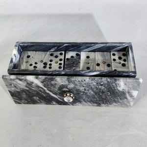 Può includere: Un set di domino in marmo bianco e nero in una scatola di marmo con un pomello d'argento. La scatola ha un motivo a marmo bianco e nero.