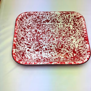 May include: Rectangular enamelware tray with a white base and a red splatter pattern. The tray has a black rim and is likely used for serving or baking. A classic kitchenware item.
