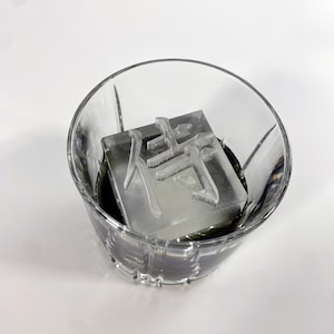 May include: A clear glass with a single ice cube that has the Chinese character "静" (pronounced "jing") carved into it.