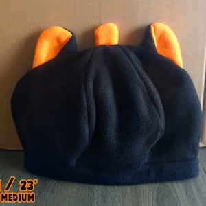 May include: Black fleece beanie with orange ear flaps. The beanie is 23 inches in circumference and is labeled "Adult Medium".