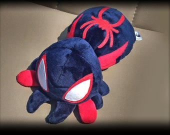 Puede incluir: Dos juguetes de peluche con forma de araña, uno negro con un diseño de araña roja y el otro negro con detalles rojos y ojos blancos.