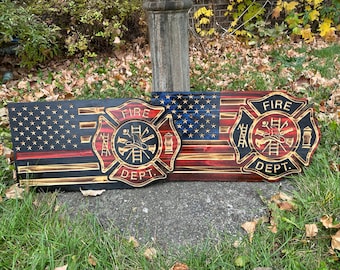 May include: Two wooden American flag signs featuring a firefighter's Maltese cross emblem. The flags are painted in red, white, and blue with a distressed wood look. The crosses are painted in black with gold accents. The text "FIRE DEPT." is on each cross.