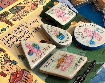Könnte beinhalten: Ein Set aus neun Keramik-Anstecknadeln mit bunten Illustrationen und Text. Die Anstecknadeln zeigen verschiedene Designs, darunter eine Katze, eine Pflanze, ein Lebensmittelgeschäft, ein Haus und eine Person, die Pflanzen gießt. Die Anstecknadeln sind handgefertigt mit tauben Fingern und trockenen Augen.